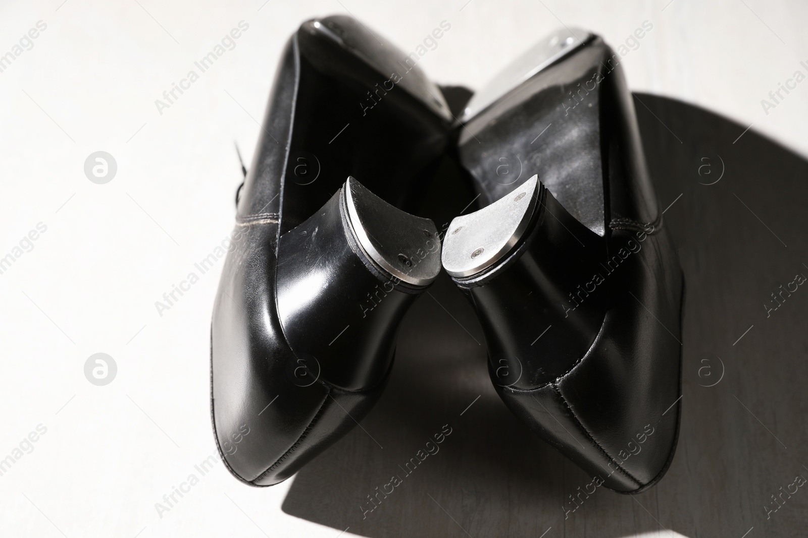 Photo of Pair of shoes for tap dance on white wooden floor, closeup