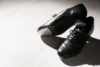 Photo of Pair of shoes for tap dance on white wooden floor. Space for text