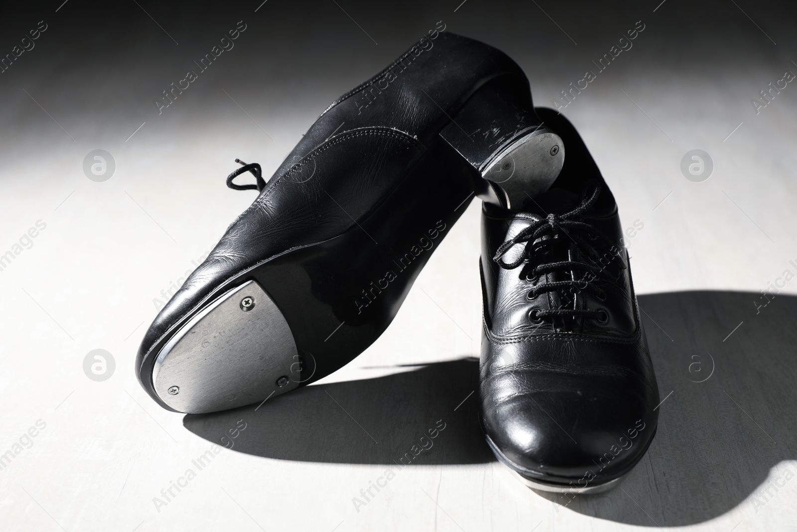 Photo of Pair of shoes for tap dance on white wooden floor, closeup