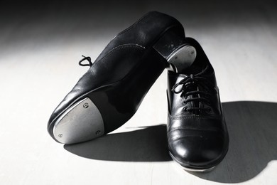 Photo of Pair of shoes for tap dance on white wooden floor, closeup