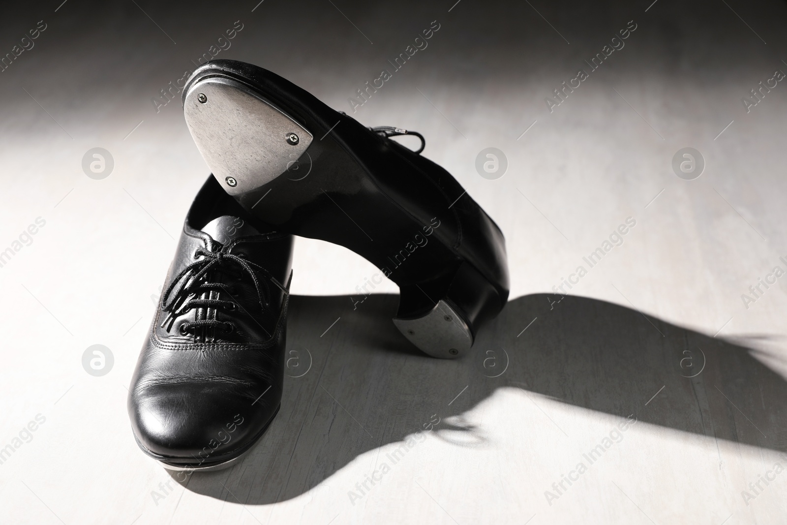 Photo of Pair of shoes for tap dance on white wooden floor. Space for text