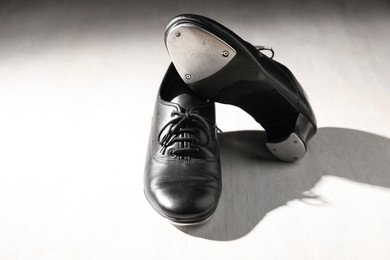 Photo of Pair of shoes for tap dance on white wooden floor