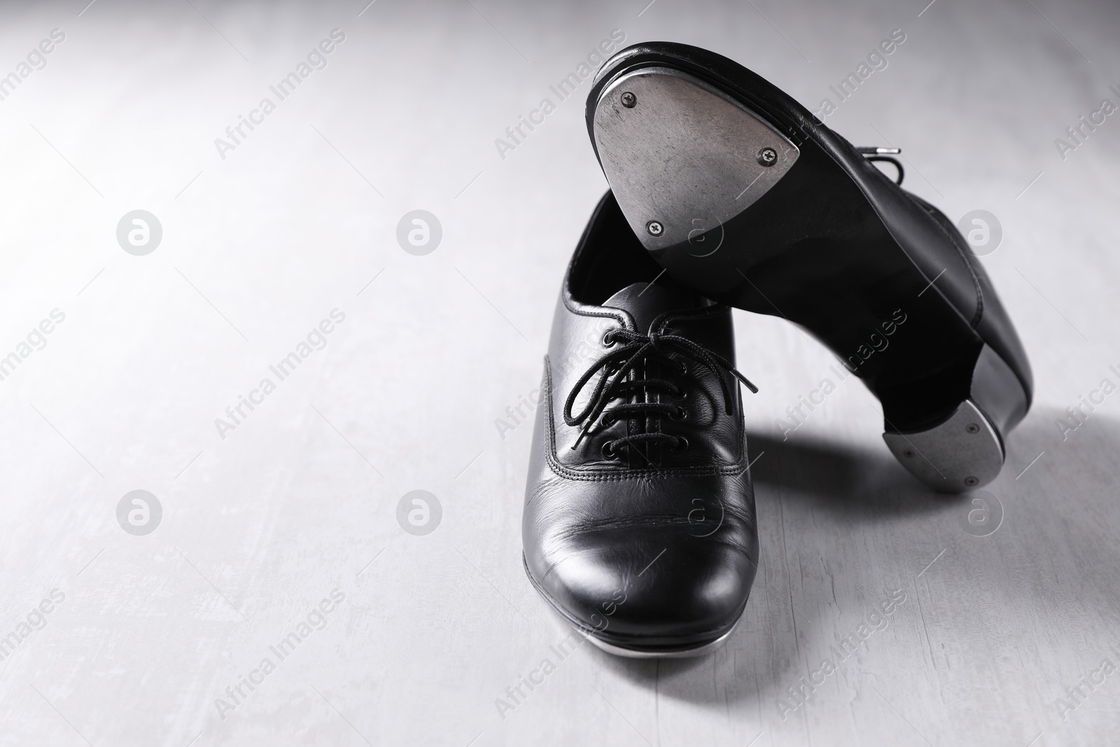 Photo of Pair of shoes for tap dance on white wooden floor. Space for text