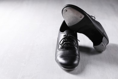 Photo of Pair of shoes for tap dance on white wooden floor. Space for text