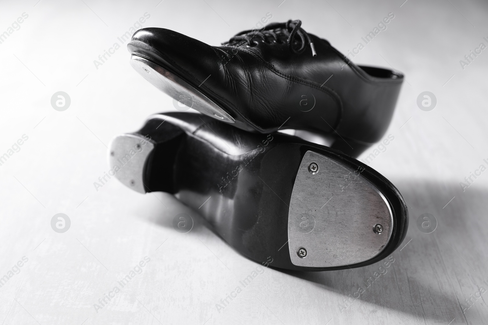 Photo of Pair of shoes for tap dance on white wooden floor, closeup