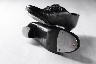 Photo of Pair of shoes for tap dance on white wooden floor, closeup