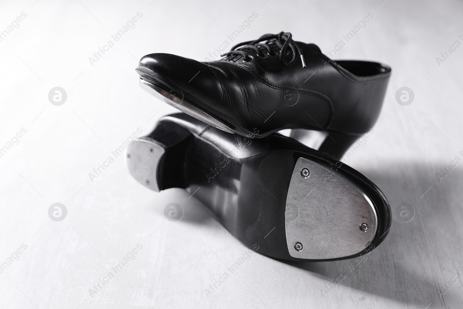 Photo of Pair of shoes for tap dance on white wooden floor, closeup