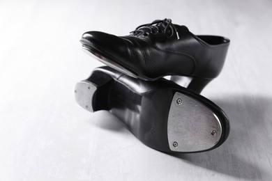 Photo of Pair of shoes for tap dance on white wooden floor, closeup