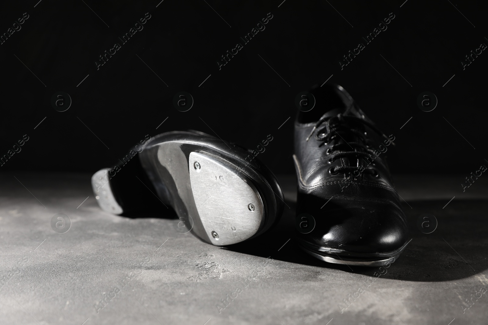 Photo of Pair of shoes for tap dance on grey surface against black background