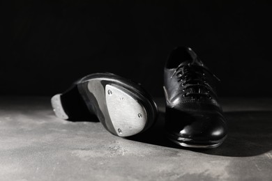 Photo of Pair of shoes for tap dance on grey surface against black background