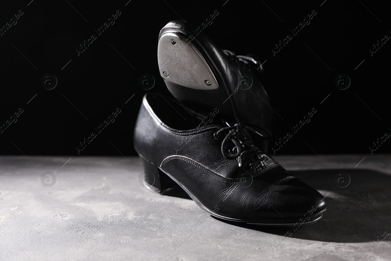 Photo of Pair of shoes for tap dance on grey surface against black background