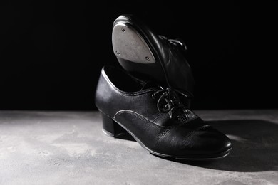 Photo of Pair of shoes for tap dance on grey surface against black background