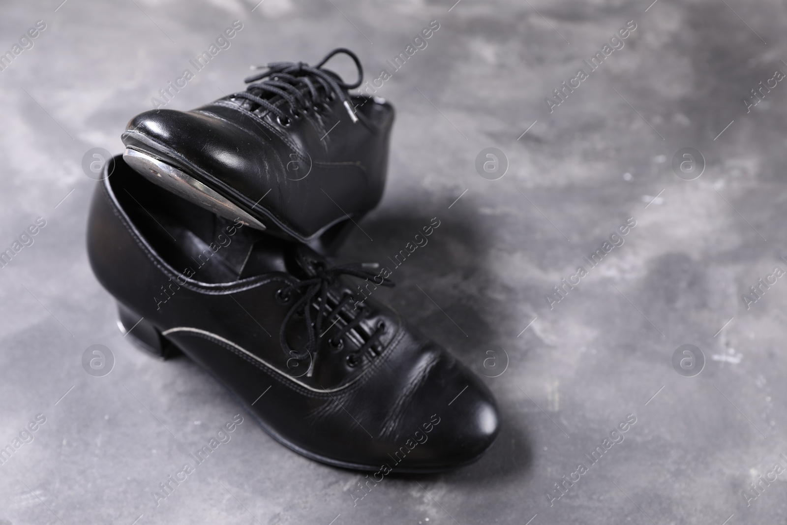 Photo of Pair of shoes for tap dance on grey surface, closeup. Space for text