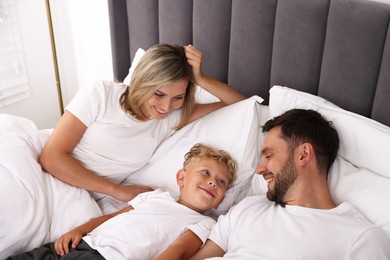 Photo of Happy family spending time together on bed at home