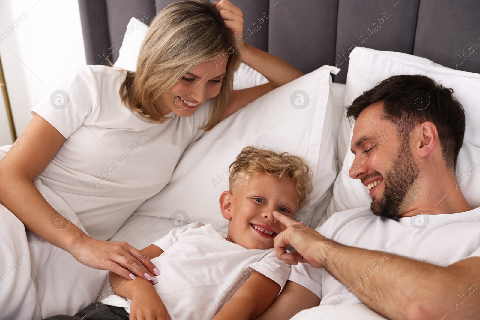 Photo of Happy family spending time together on bed at home