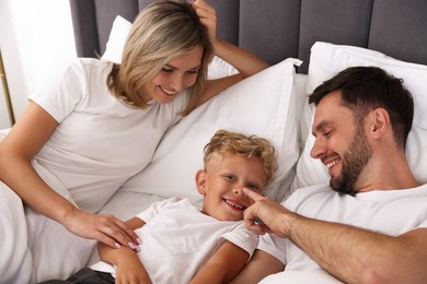 Photo of Happy family spending time together on bed at home