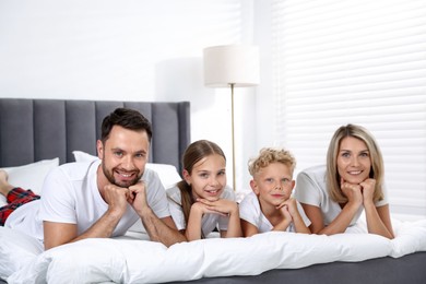 Photo of Family portrait of happy parents and their children on bed at home