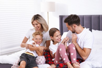 Photo of Happy family having fun on bed at home