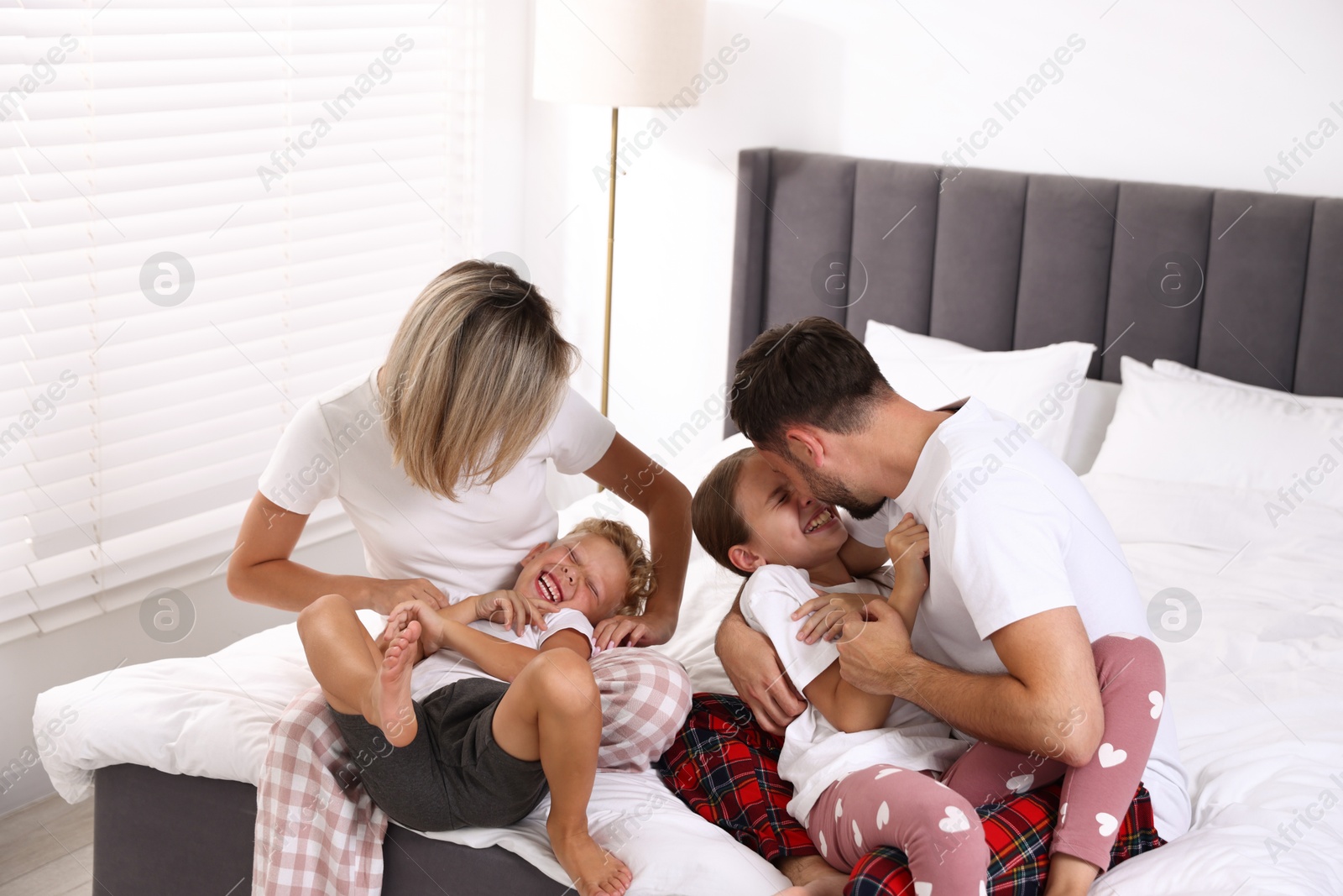 Photo of Happy family having fun on bed at home