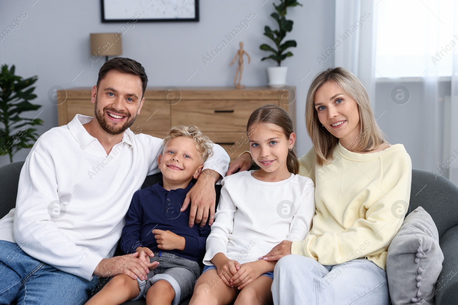 Photo of Happy family sitting on sofa at home