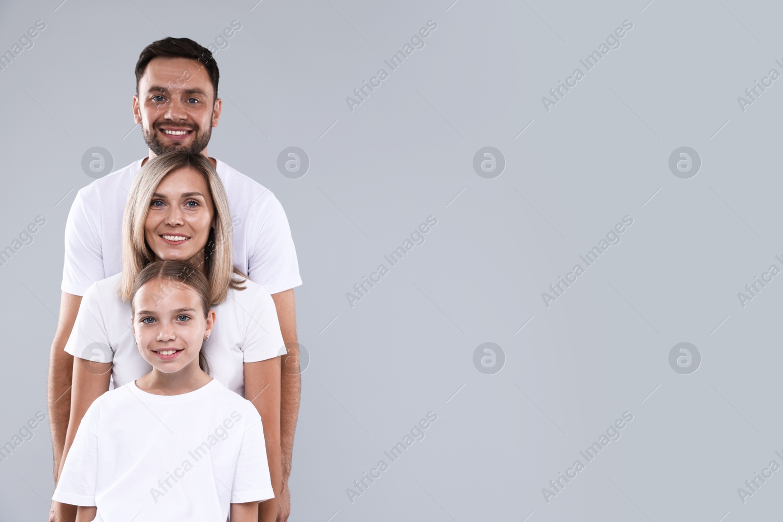 Photo of Family portrait of happy parents and their daughter on grey background. Space for text