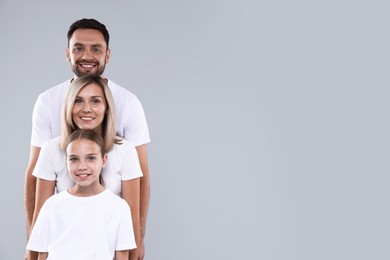 Photo of Family portrait of happy parents and their daughter on grey background. Space for text