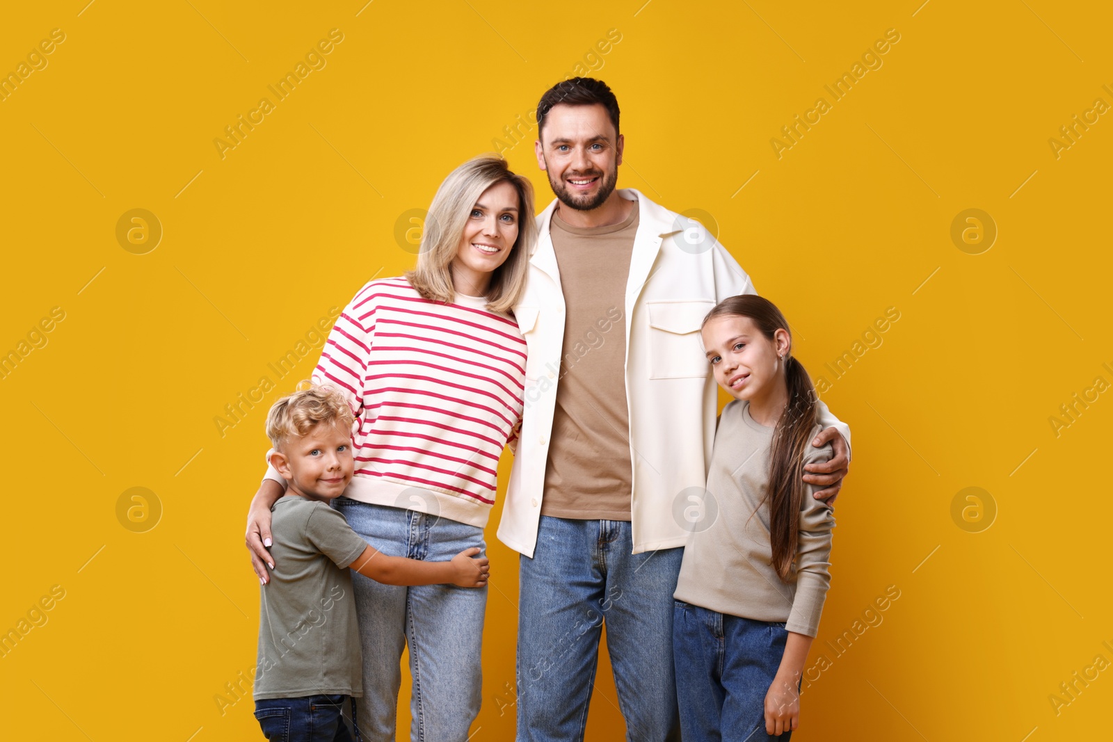 Photo of Family portrait of happy parents and their children on yellow background