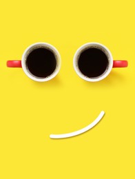 Image of Coffee in cups and line making smiling face on yellow background, top view