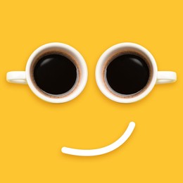 Image of Coffee in cups and line making smiling face on orange background, top view