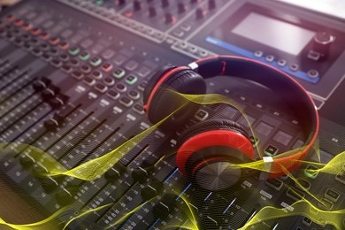 Image of Headphones on professional mixing console and sound waves