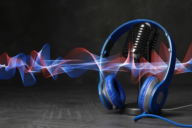 Image of Headphones, microphone and sound waves against black background
