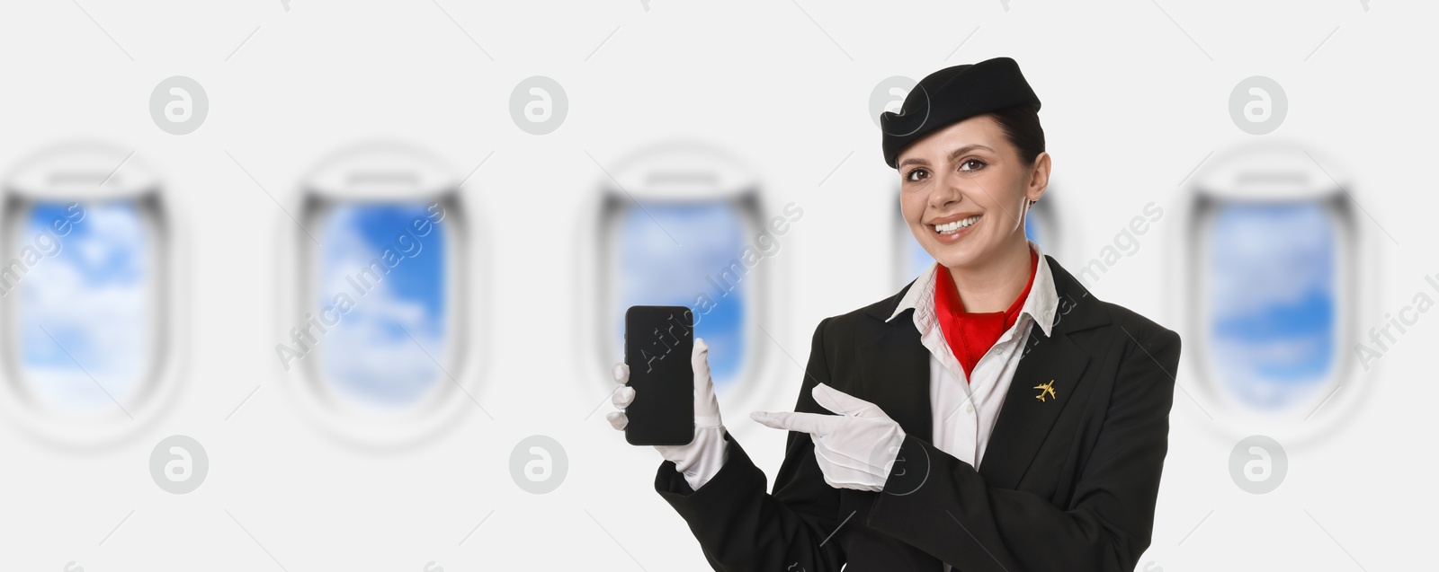 Image of Air hostess pointing at mobile phone near windows in plane