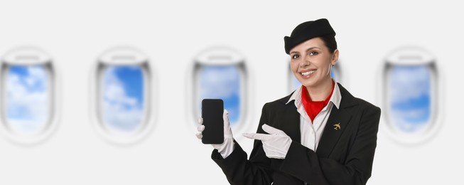 Image of Air hostess pointing at mobile phone near windows in plane