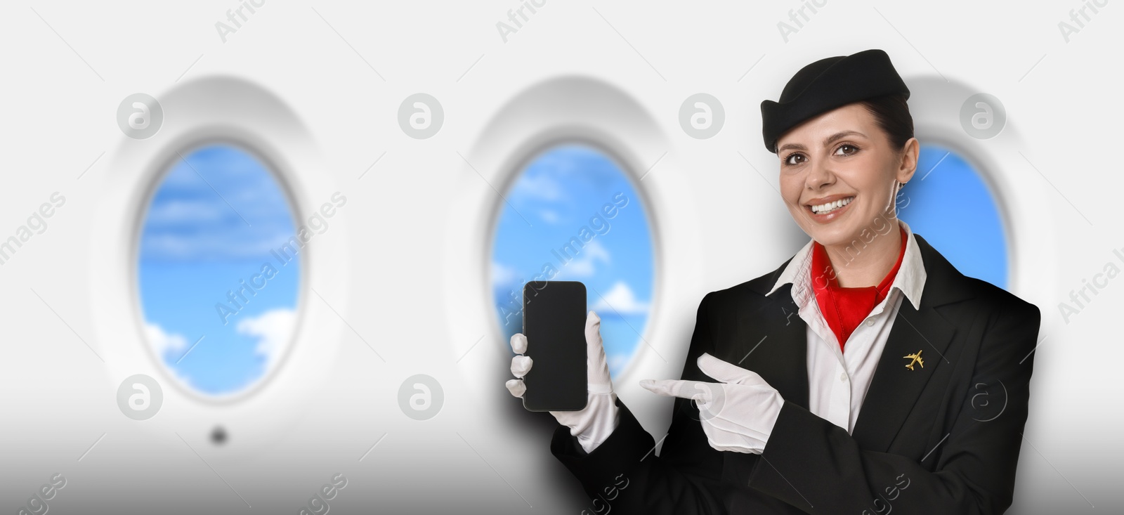 Image of Air hostess pointing at mobile phone near windows in plane
