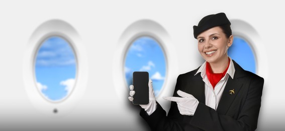 Image of Air hostess pointing at mobile phone near windows in plane