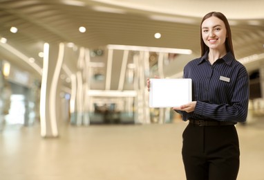 Image of Young hostess with tablet computer in hotel lobby. Space for text