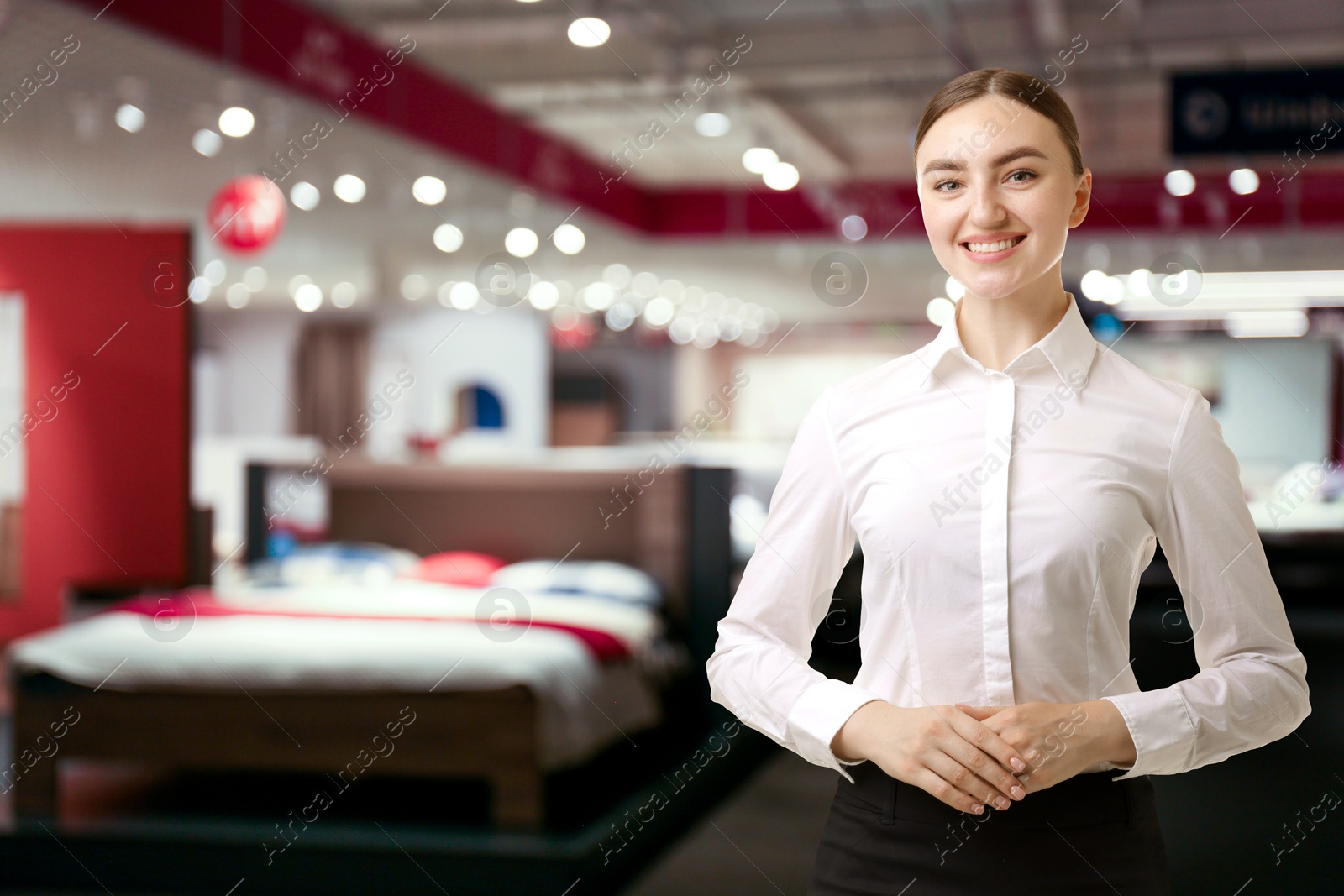 Young hostess smiling in furniture store. Space for text Image of Young hostess smiling in furniture store. Space for text