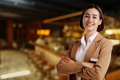 Image of Young hostess smiling in restaurant. Space for text