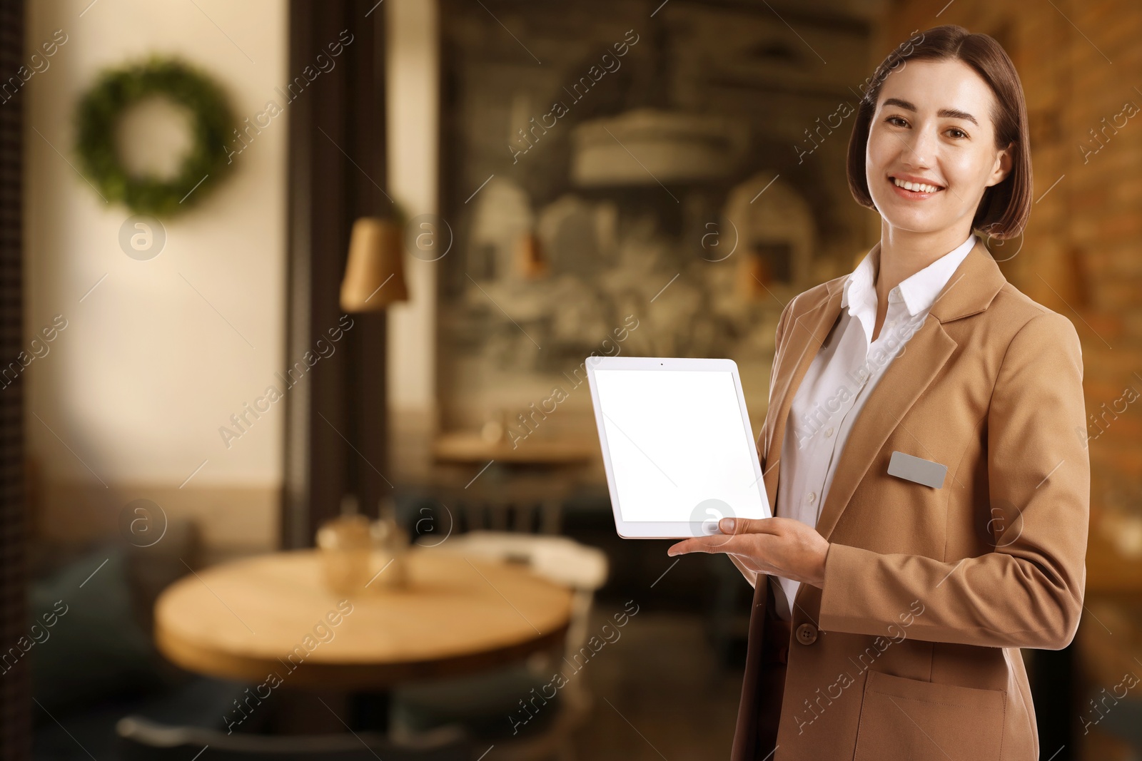 Young hostess with tablet computer in restaurant. Space for text Image of Young hostess with tablet computer in restaurant. Space for text