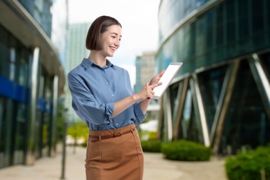 Image of Young hostess using tablet computer near hotel outdoors