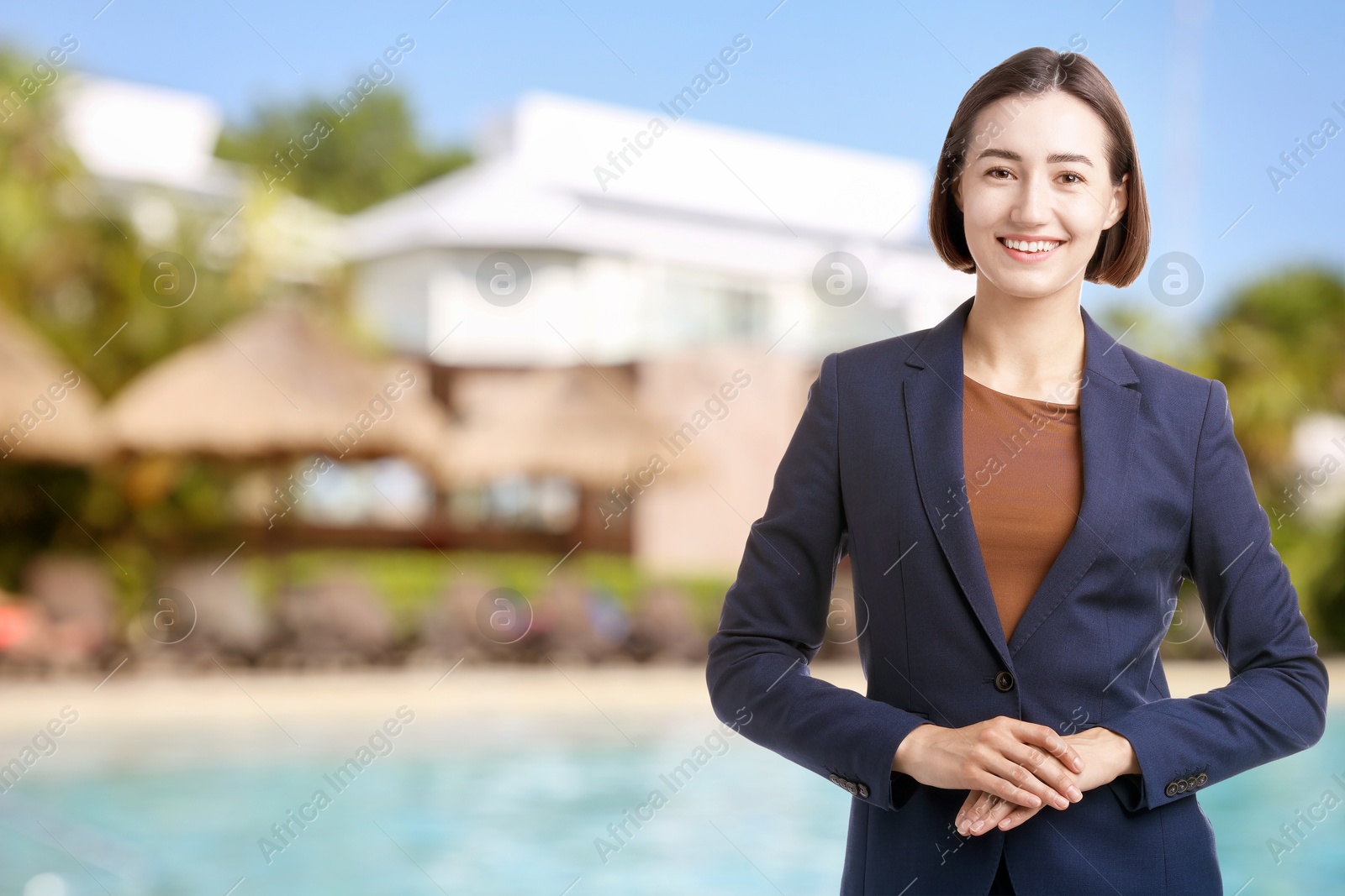 Young hostess smiling near resort outdoors. Space for text Image of Young hostess smiling near resort outdoors. Space for text