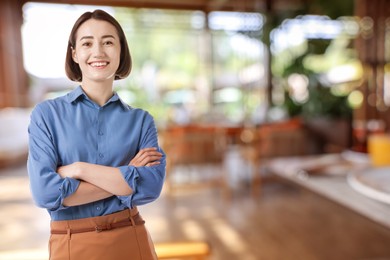 Image of Young hostess smiling in restaurant. Space for text