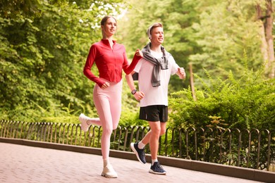 Photo of Happy couple running in park, low angle view. Morning exercise