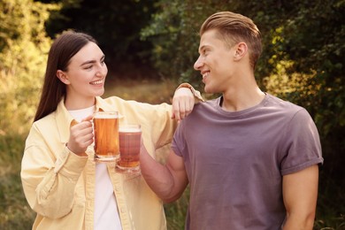 Photo of Young man and woman with glasses of beer having fun outdoors