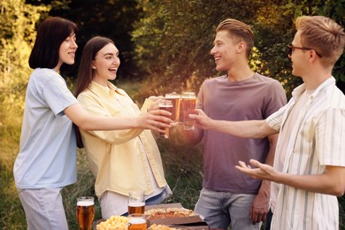 Photo of Group of happy friends clinking glasses of beer outdoors