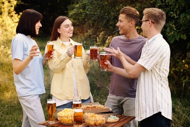 Photo of Group of happy friends clinking glasses of beer outdoors