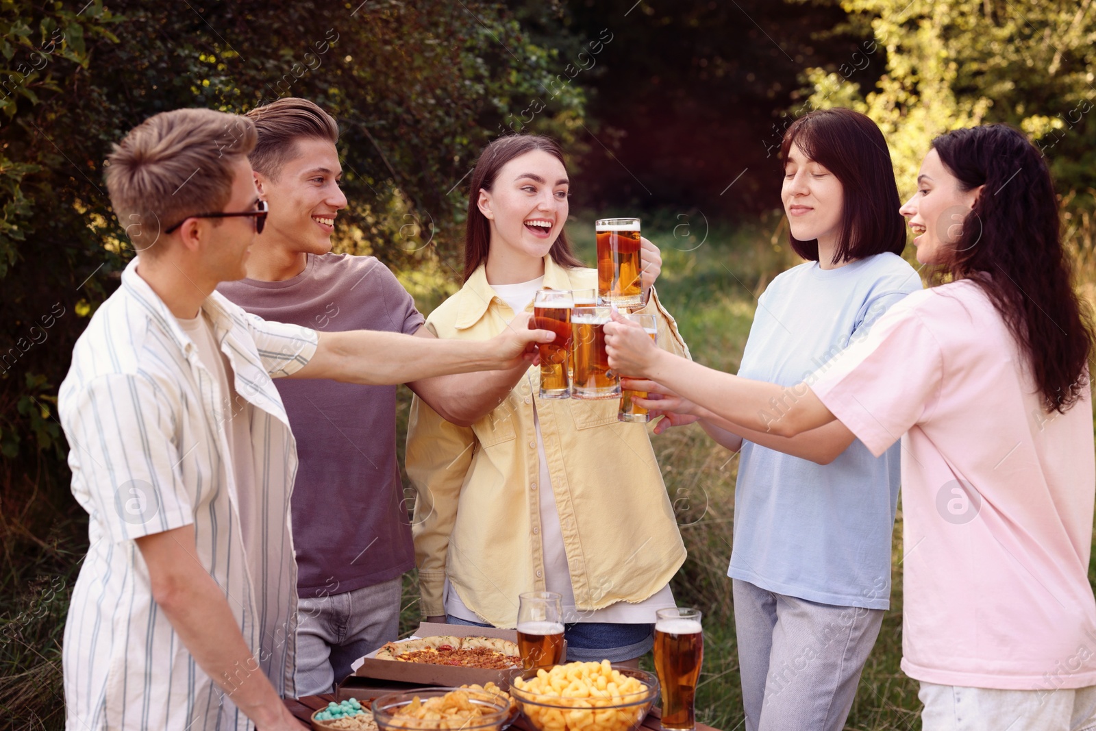 Group of happy friends clinking glasses of beer outdoors Photo of Group of happy friends clinking glasses of beer outdoors