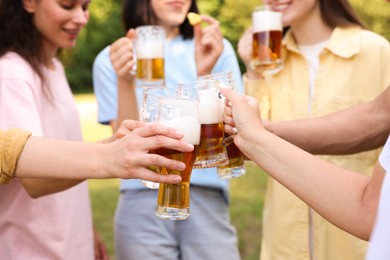 Photo of Group of happy friends clinking glasses of beer outdoors, selective focus