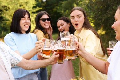 Photo of Group of happy friends clinking glasses of beer outdoors, selective focus
