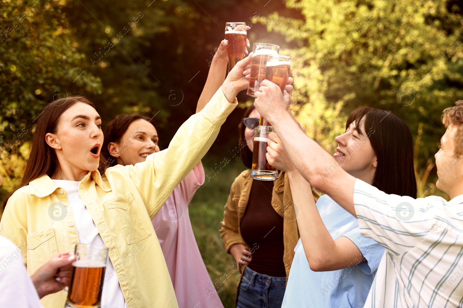 Photo of Group of happy friends clinking glasses of beer outdoors